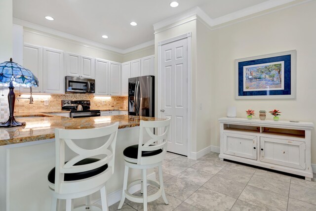 living room with ceiling fan, a barn door, built in features, and ornamental molding