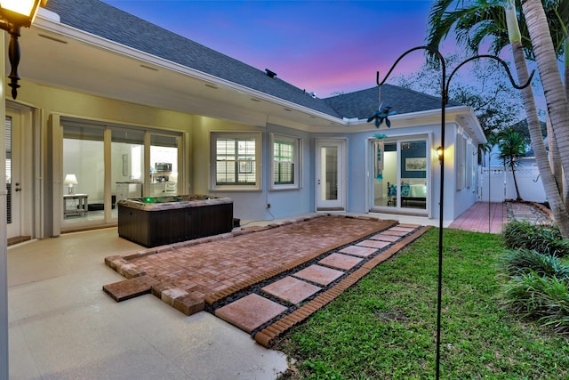 back house at dusk with a lawn and a patio area