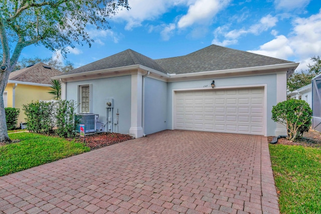 ranch-style home with central AC unit, a garage, and a front yard