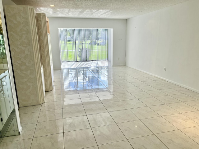 empty room with light tile patterned flooring and a textured ceiling