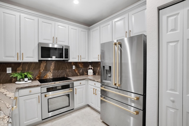 kitchen with light stone countertops, appliances with stainless steel finishes, decorative backsplash, and white cabinetry