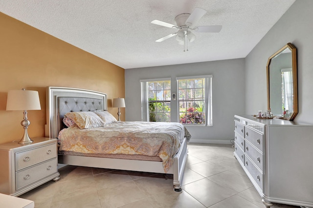 bedroom featuring ceiling fan, light tile patterned floors, and a textured ceiling