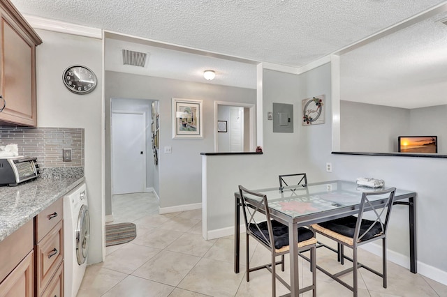 tiled dining space featuring ornamental molding, a textured ceiling, and washer / dryer