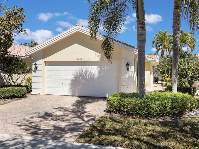 view of front of house featuring a garage, decorative driveway, and stucco siding