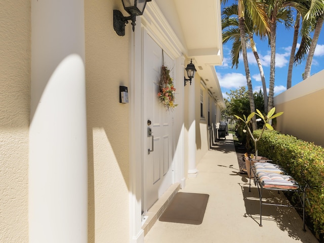 entrance to property featuring fence and stucco siding