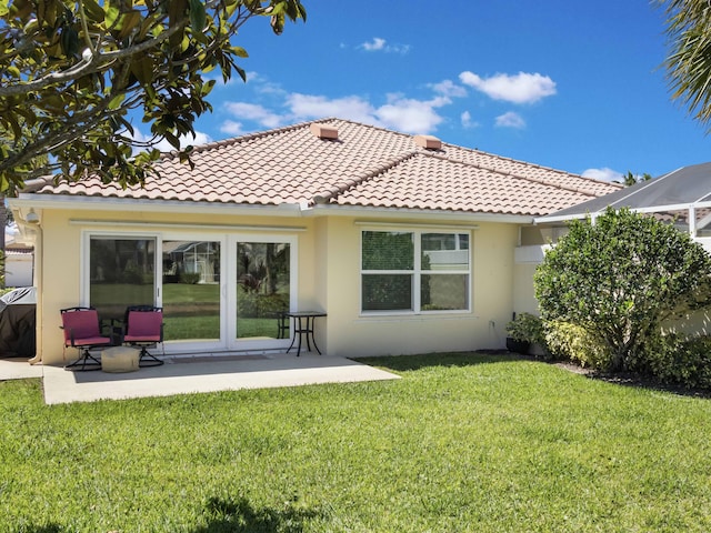 rear view of house with a tile roof, a lawn, a patio, and stucco siding