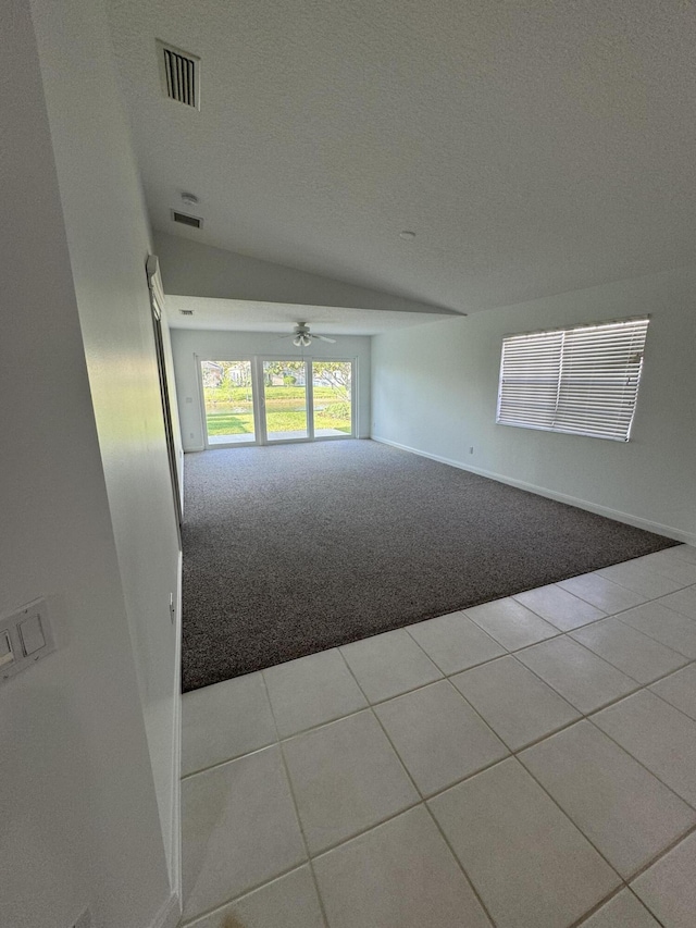 empty room featuring a textured ceiling, lofted ceiling, light colored carpet, and ceiling fan