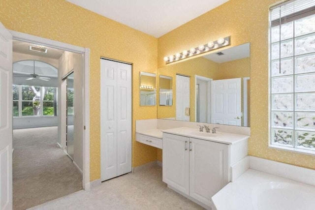 bathroom featuring vanity, a tub to relax in, and ceiling fan