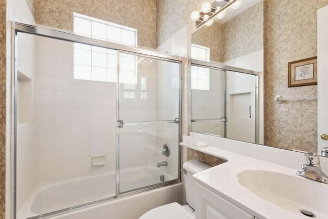 full bathroom featuring vanity, toilet, and combined bath / shower with glass door