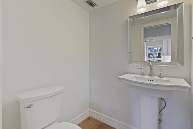 half bath featuring visible vents, toilet, baseboards, and wood finished floors