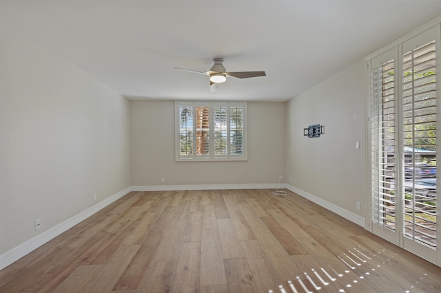 unfurnished room with a ceiling fan, light wood-type flooring, and baseboards