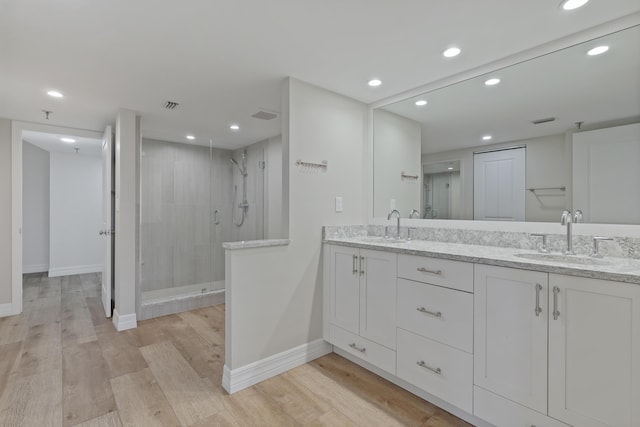 bathroom featuring a stall shower, a sink, and wood finished floors