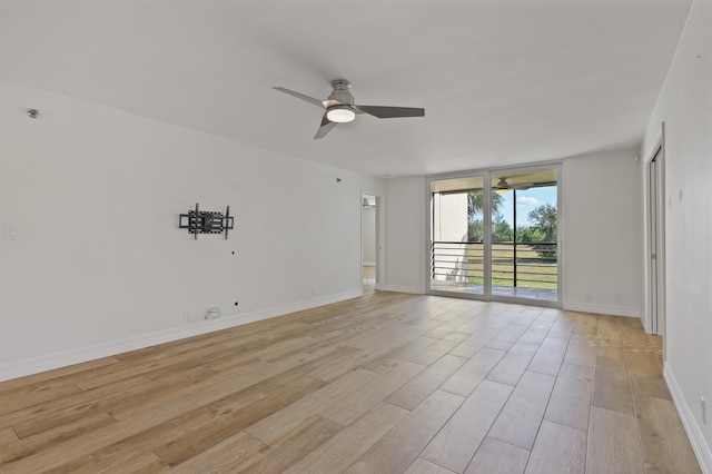 unfurnished room with floor to ceiling windows, light wood-type flooring, a ceiling fan, and baseboards