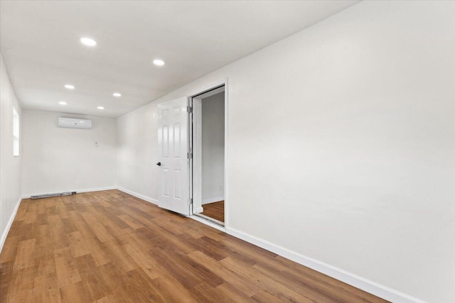 unfurnished room with wood-type flooring and an AC wall unit