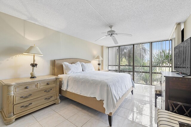 tiled bedroom with ceiling fan, expansive windows, a textured ceiling, and access to outside