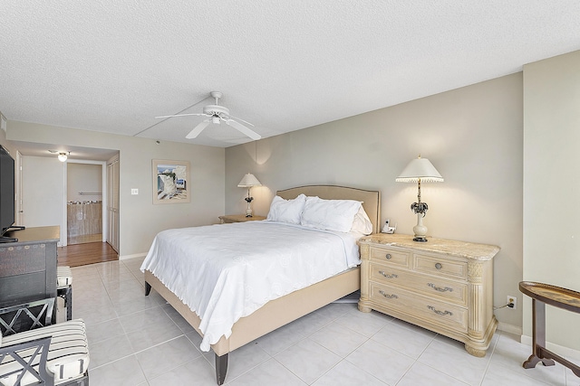 bedroom featuring ceiling fan, light tile patterned flooring, and a textured ceiling