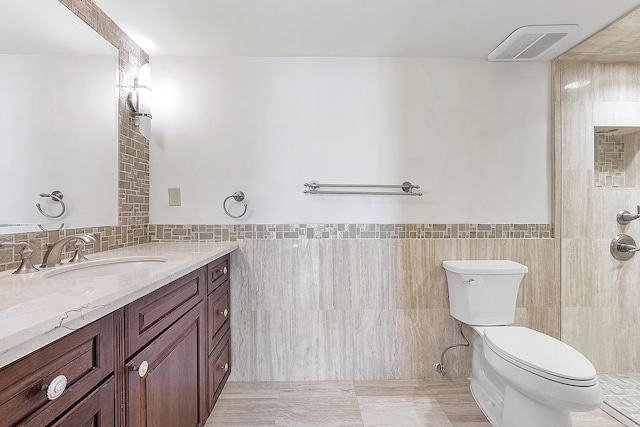 bathroom featuring walk in shower, vanity, tile walls, and toilet