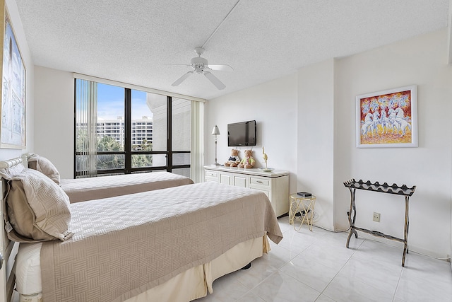 tiled bedroom with ceiling fan, expansive windows, and a textured ceiling