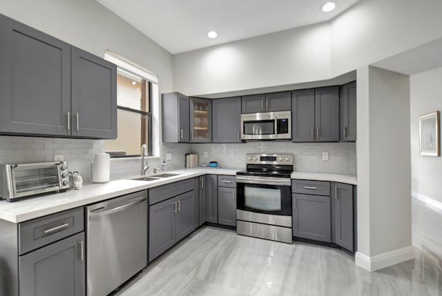 kitchen featuring appliances with stainless steel finishes, gray cabinets, tasteful backsplash, and sink