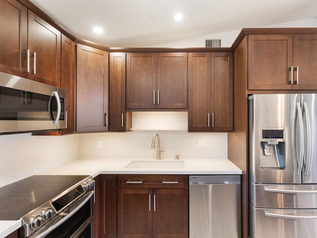 kitchen featuring appliances with stainless steel finishes, light stone countertops, sink, and backsplash