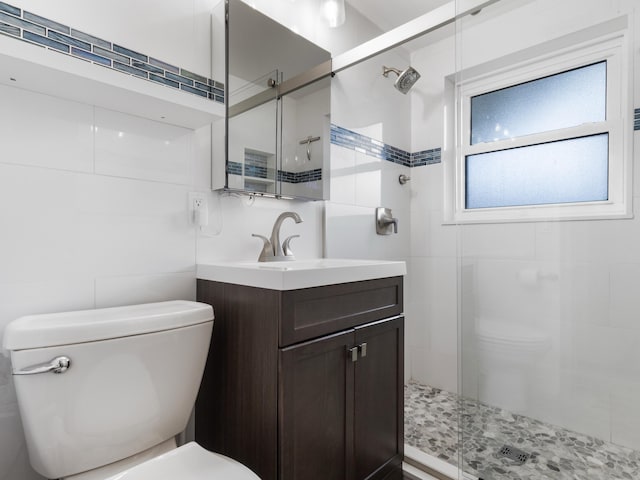 bathroom with walk in shower, vanity, toilet, and tile walls