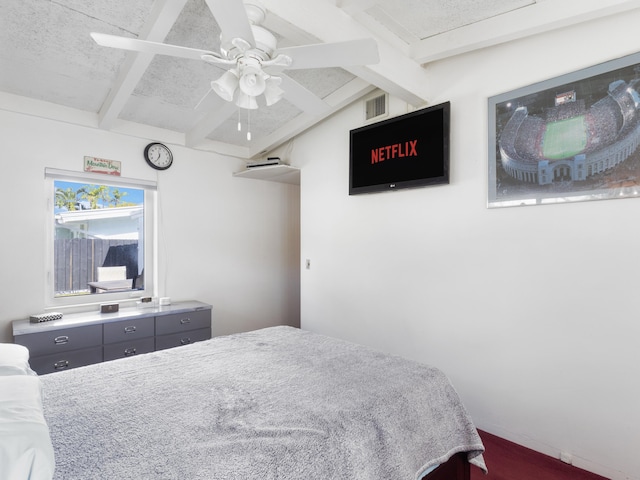 bedroom featuring ceiling fan, lofted ceiling with beams, and a textured ceiling