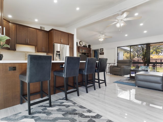 kitchen with vaulted ceiling with beams, kitchen peninsula, a kitchen bar, and stainless steel fridge with ice dispenser