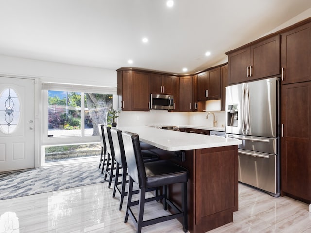 kitchen featuring a kitchen bar, dark brown cabinets, sink, and appliances with stainless steel finishes