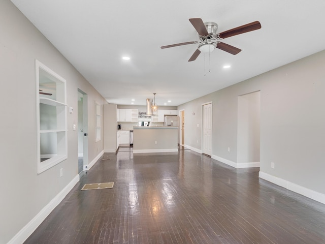 unfurnished living room featuring built in shelves, ceiling fan, and dark wood-type flooring