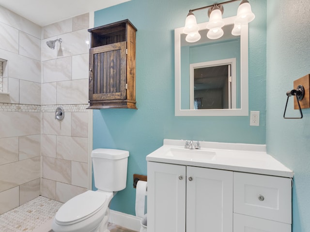 bathroom featuring tiled shower, vanity, and toilet