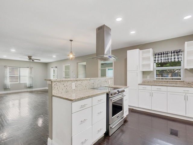 kitchen with island exhaust hood, high end stainless steel range, white cabinets, and decorative light fixtures