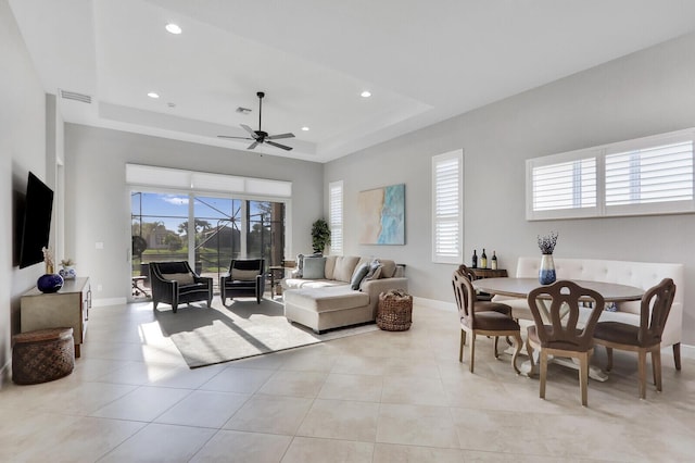 tiled living room with a tray ceiling and ceiling fan