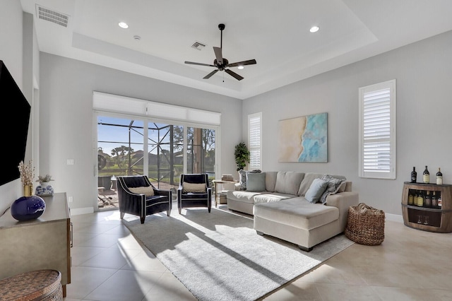 living room featuring a raised ceiling, a wealth of natural light, and ceiling fan