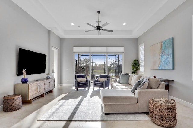 tiled living room featuring a tray ceiling and ceiling fan