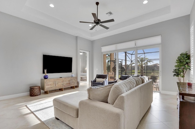 tiled living room featuring ceiling fan and a raised ceiling