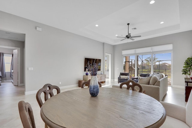 dining area featuring a raised ceiling and ceiling fan