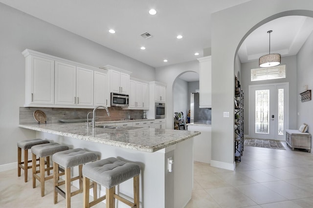 kitchen featuring white cabinets, hanging light fixtures, appliances with stainless steel finishes, tasteful backsplash, and kitchen peninsula