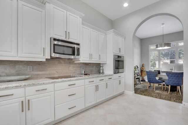 kitchen featuring light stone countertops, tasteful backsplash, stainless steel appliances, white cabinetry, and hanging light fixtures