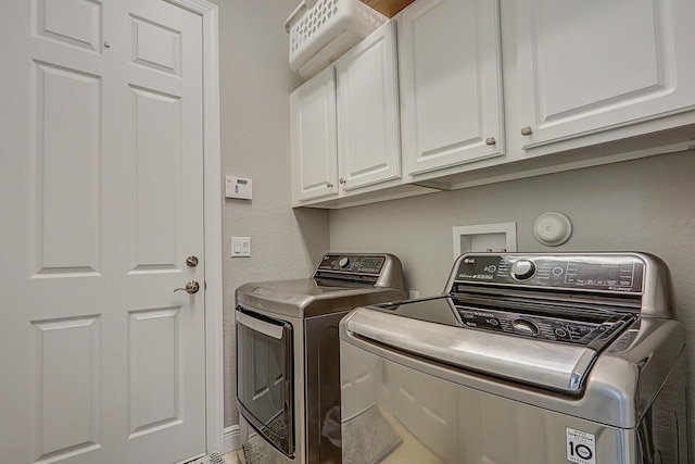 clothes washing area with washing machine and clothes dryer and cabinets