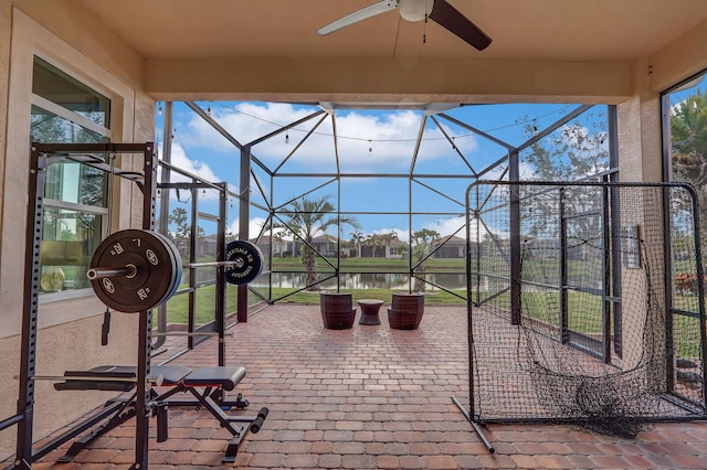 view of patio / terrace featuring a lanai, ceiling fan, and a water view