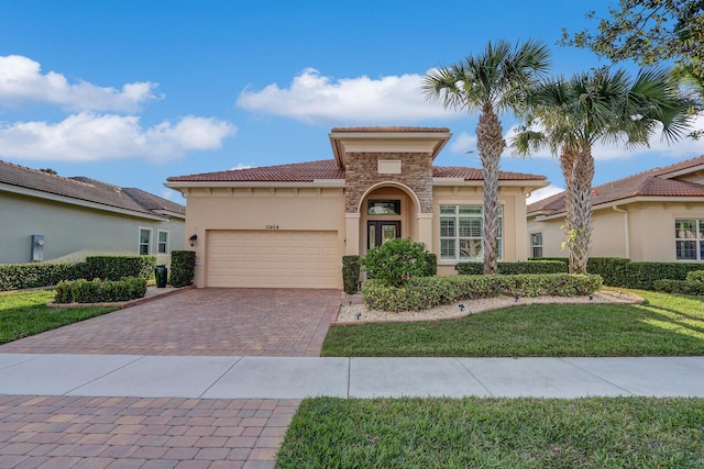 mediterranean / spanish-style home featuring a front yard and a garage