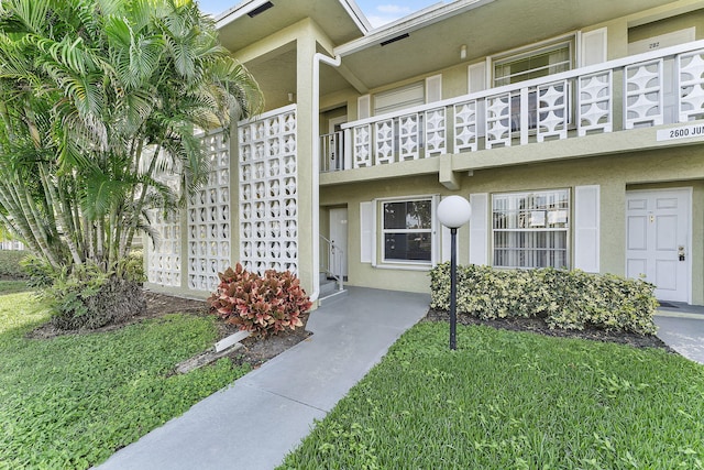 property entrance featuring a balcony and a lawn