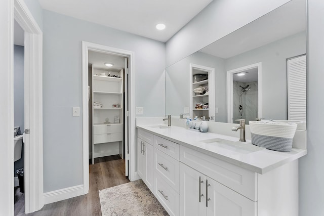 bathroom with a shower, vanity, hardwood / wood-style flooring, and built in features