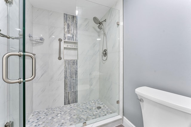 bathroom featuring toilet and a shower with door