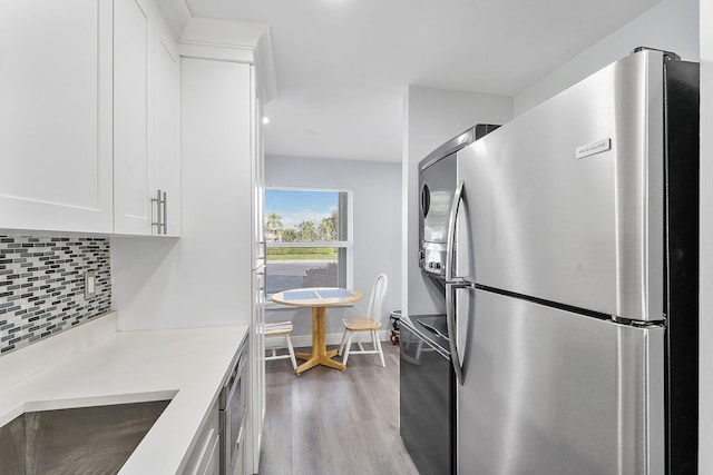 kitchen with white cabinetry, tasteful backsplash, stove, light hardwood / wood-style flooring, and stainless steel refrigerator