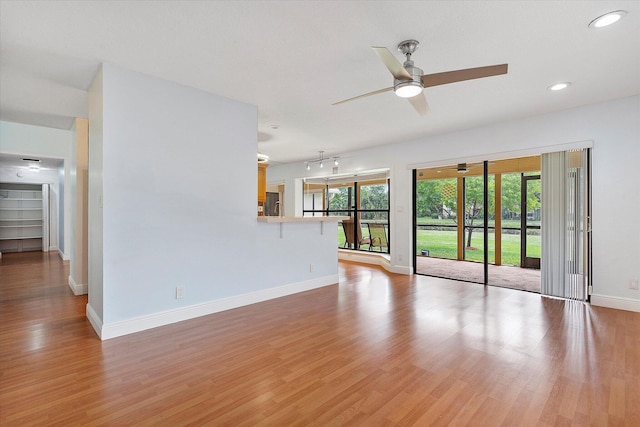 unfurnished living room featuring ceiling fan, plenty of natural light, and light wood-type flooring