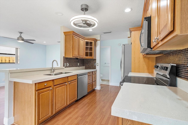 kitchen featuring sink, ceiling fan, light hardwood / wood-style floors, kitchen peninsula, and stainless steel appliances