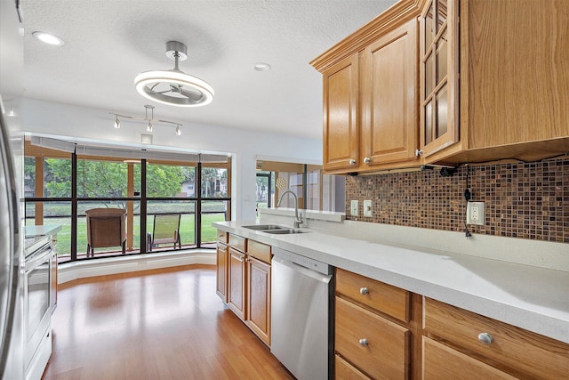 kitchen with sink, tasteful backsplash, stainless steel dishwasher, stove, and light hardwood / wood-style floors