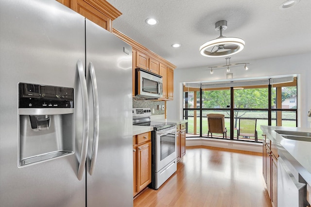 kitchen with backsplash, sink, a textured ceiling, appliances with stainless steel finishes, and decorative light fixtures