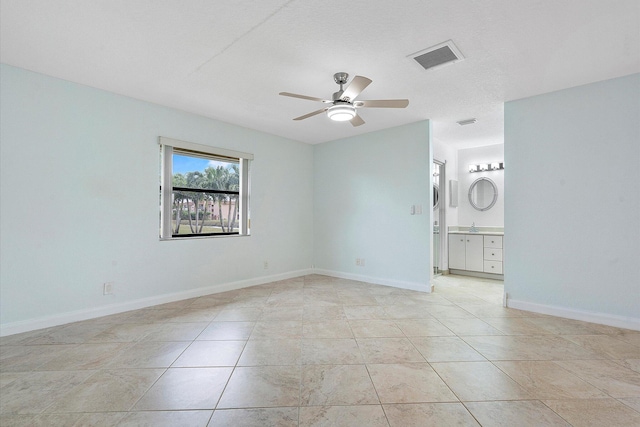 spare room featuring a textured ceiling, ceiling fan, and light tile patterned flooring